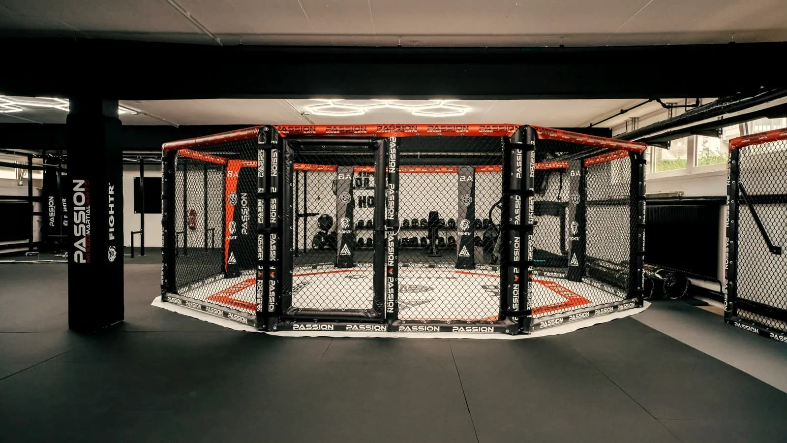 Octagon-MMA-Käfig mit roter Polsterung in einer großen Trainingshalle